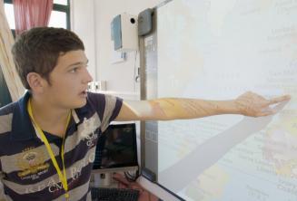 Estudante apontando para um mapa Estudante apontando para um mapa na sala de aula